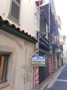 Échafaudage sur façade de rue étroite avec panneau de chantier « Couverture, Charpente, Façade »