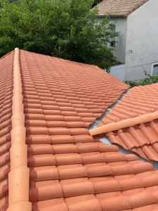 Toiture neuve en tuiles romanes rouge orangé avec faîtage, arêtier et noue en zinc