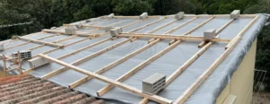 Toiture en cours de réfection avec écran sous-toiture gris, liteaux et parpaings de lestage